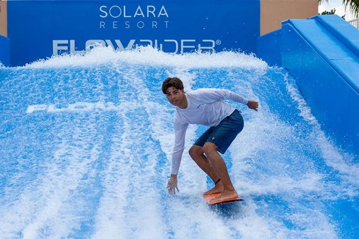 Guest riding the FlowRider surf simulator at Solara Resort