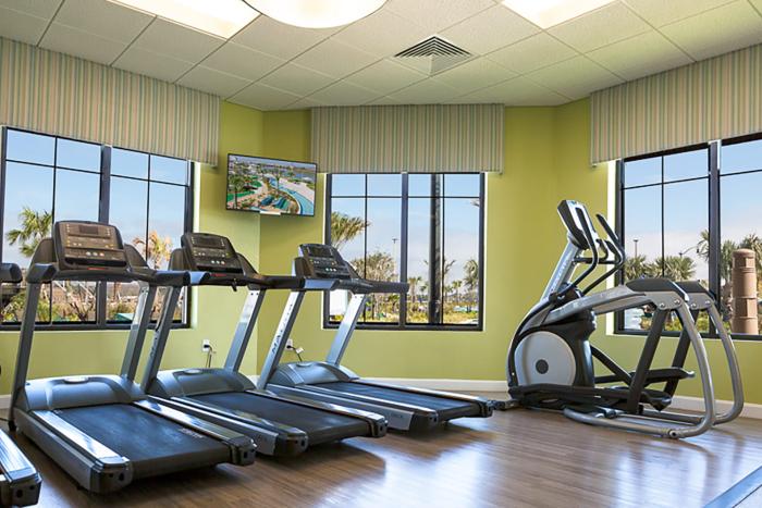 Modern resort gym featuring treadmills and an elliptical trainer facing large windows