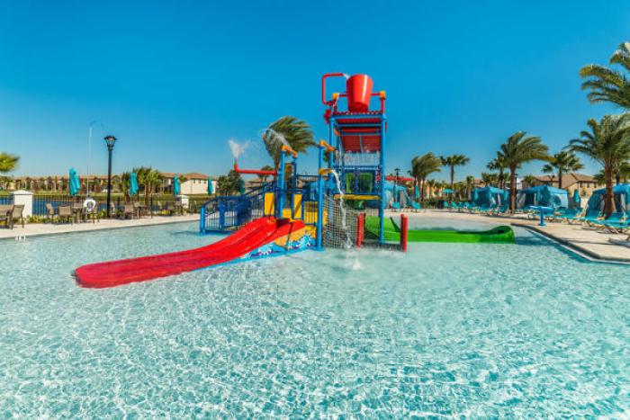 Interactive water play structure with red and green slides in the resort pool at Windsor at Westside