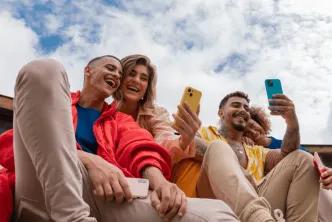 Group of friends using their smartphones while laughing.