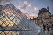 The glass pyramid of The Louvre museum in front of a sunset