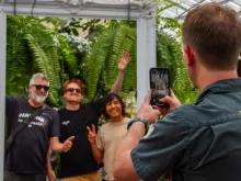 Tour guide taking a photo of three smiling people posing in a decorative frame during the Melbourne City Discovery Tour