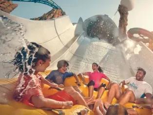Four people laughing on a water slide at Yas Waterworld.
