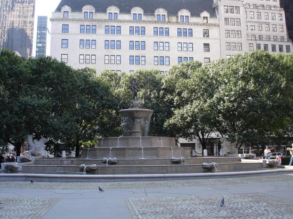 A large fountain in front trees and buildings in New York