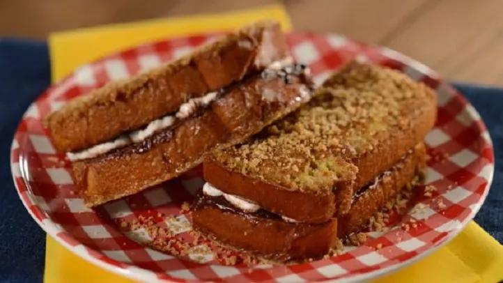A toasted sandwich filled with marshmallow and chocolate on a gingham patterned plate