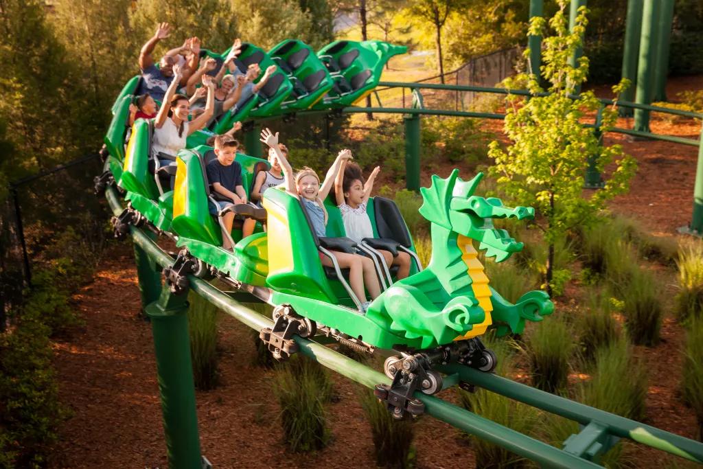 Guests riding the Dragon rollercoaster with their arms up in the air