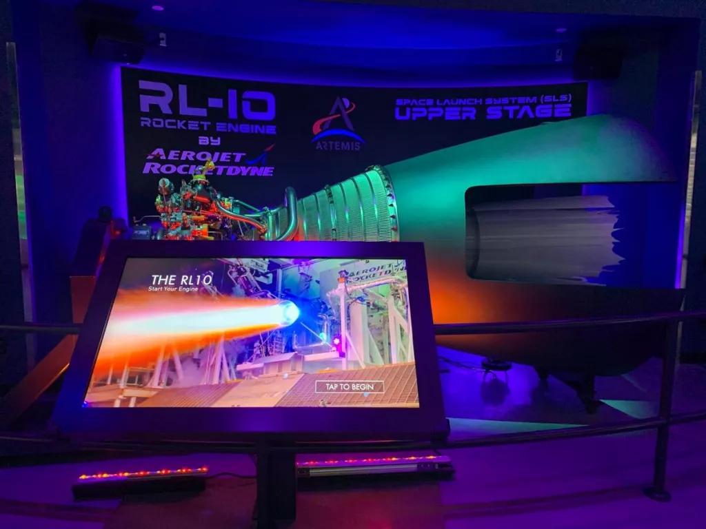 An interactive screen in front of a display of a rocket engine