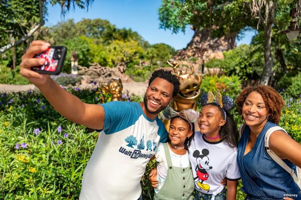 A family taking a selfie in front of the Lion King golden statues and the Tree of Life