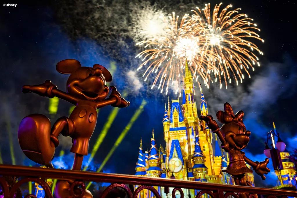 Golden statues of Mickey and Minnie in front of Cinderella Castle during the fireworks