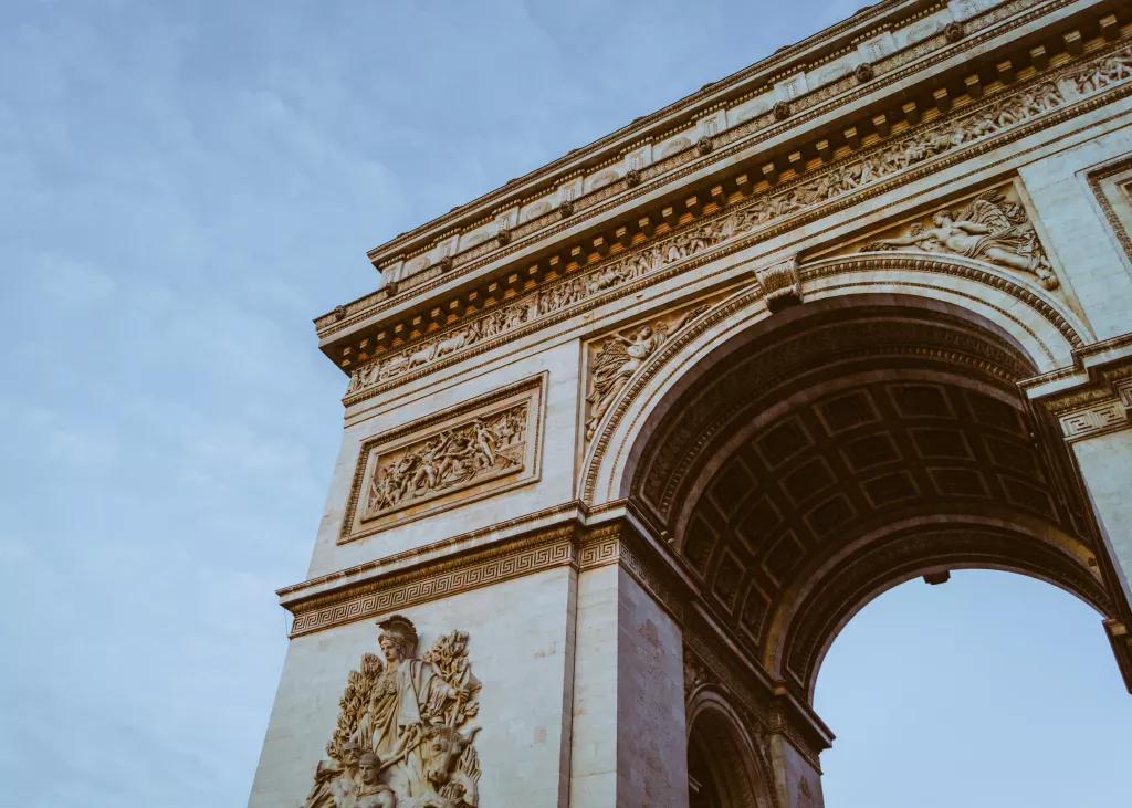 Looking up at the Arc de Triomphe in front of a blue sky