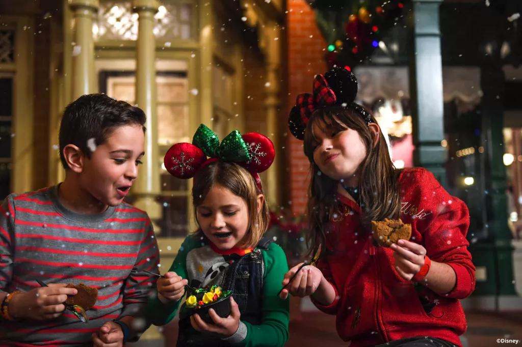 Two girls and a boy eating cookies and wearing Christmas jumpers