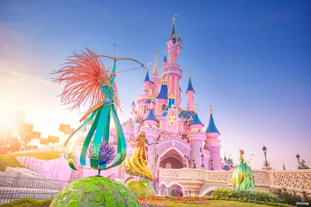 Metal sculptures of Merida, Tiana and Belle in front of Sleeping Beauty Castle