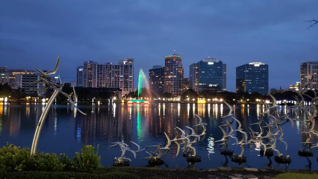 Lake Eola at night with skyscrapers in the background and bird sculptures in the foreground