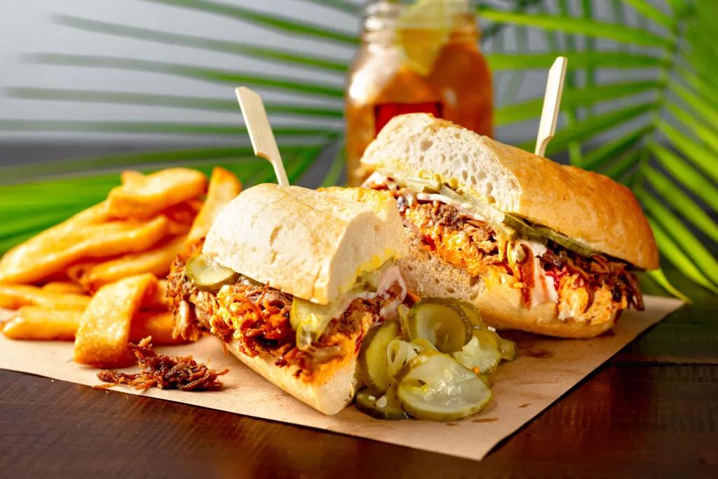 A brisket sandwich served with fries and pickles