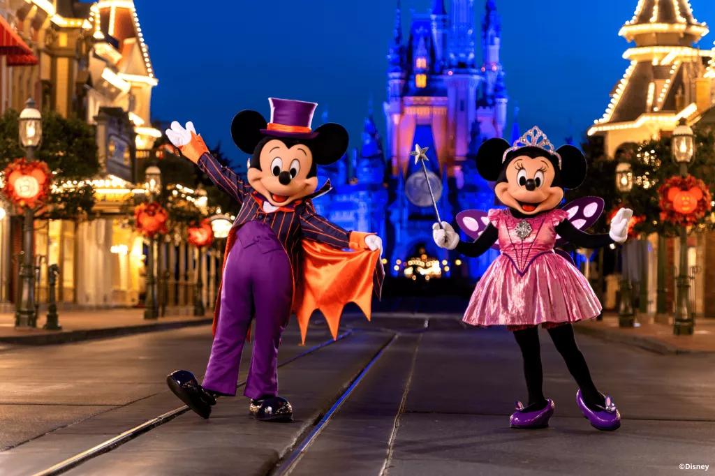 Mickey and Minnie in Halloween costumes in front of Cinderella Castle