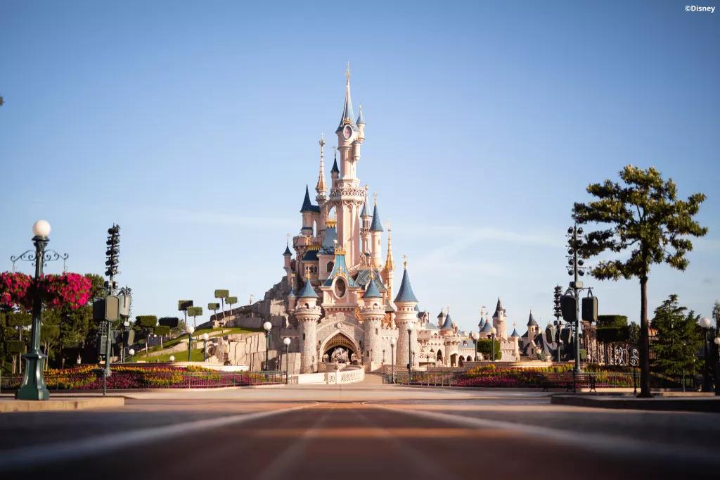 A view down Main Street of Sleeping Beauty Castle in front of a bright blue sky