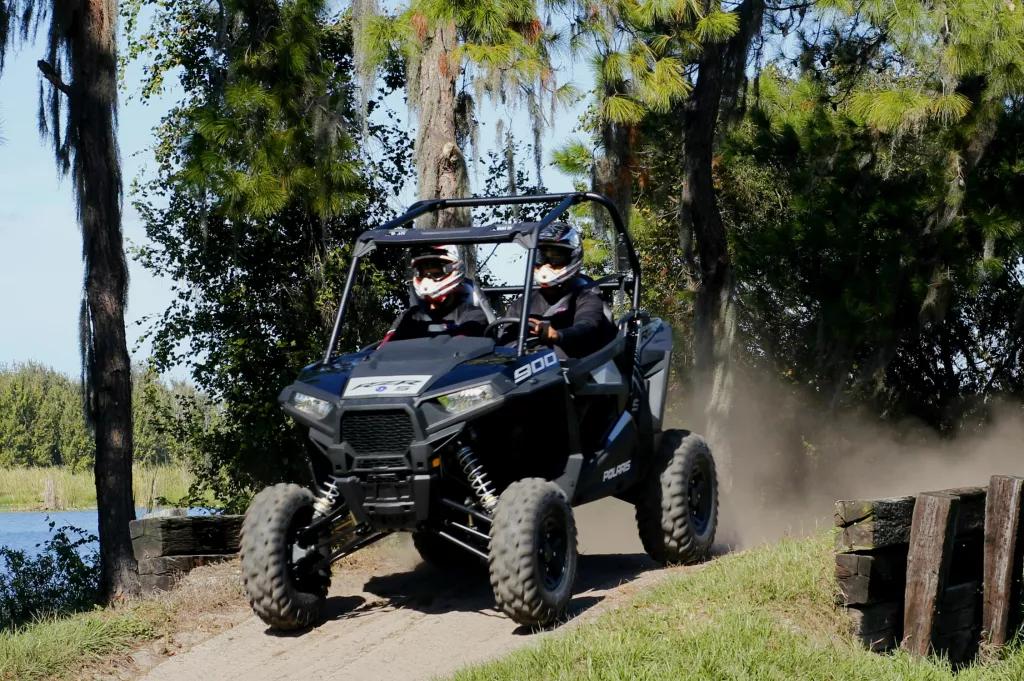 Two people in helmets sat next to each other in a 4x4 off road vehicle