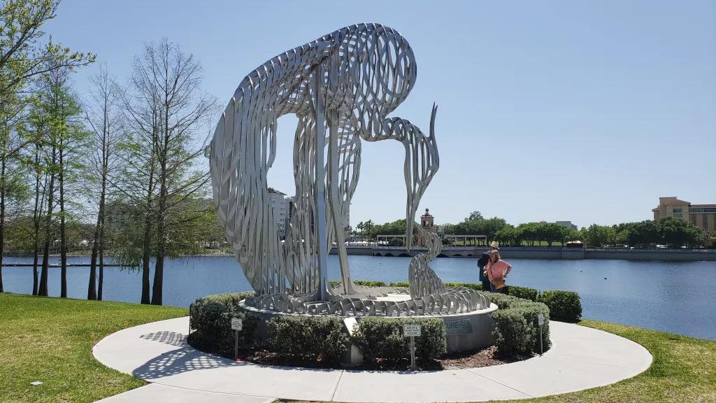 A metal sculpture of a crane in front of a large lake