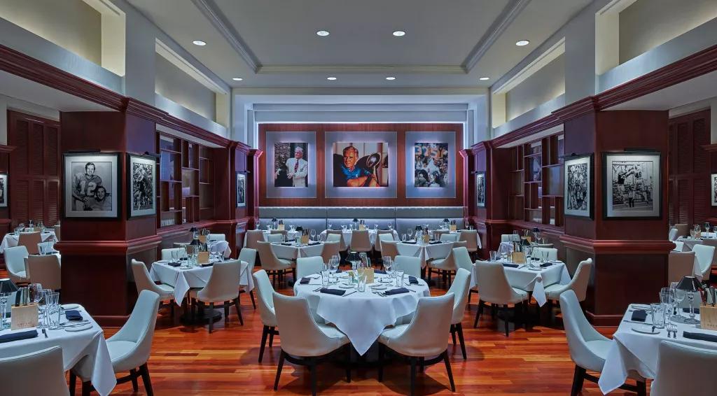 The dining room at Shula's Steakhouse, with multiple tables laid with linen table cloths and cutlery