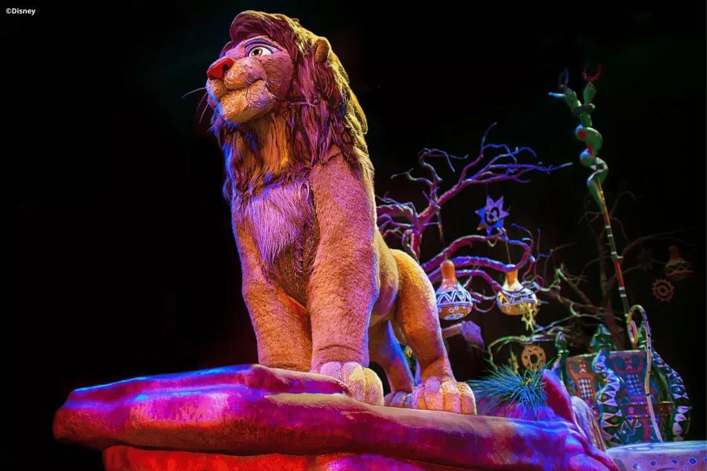 A Simba animatronic on a float decorated to look like Pride Rock