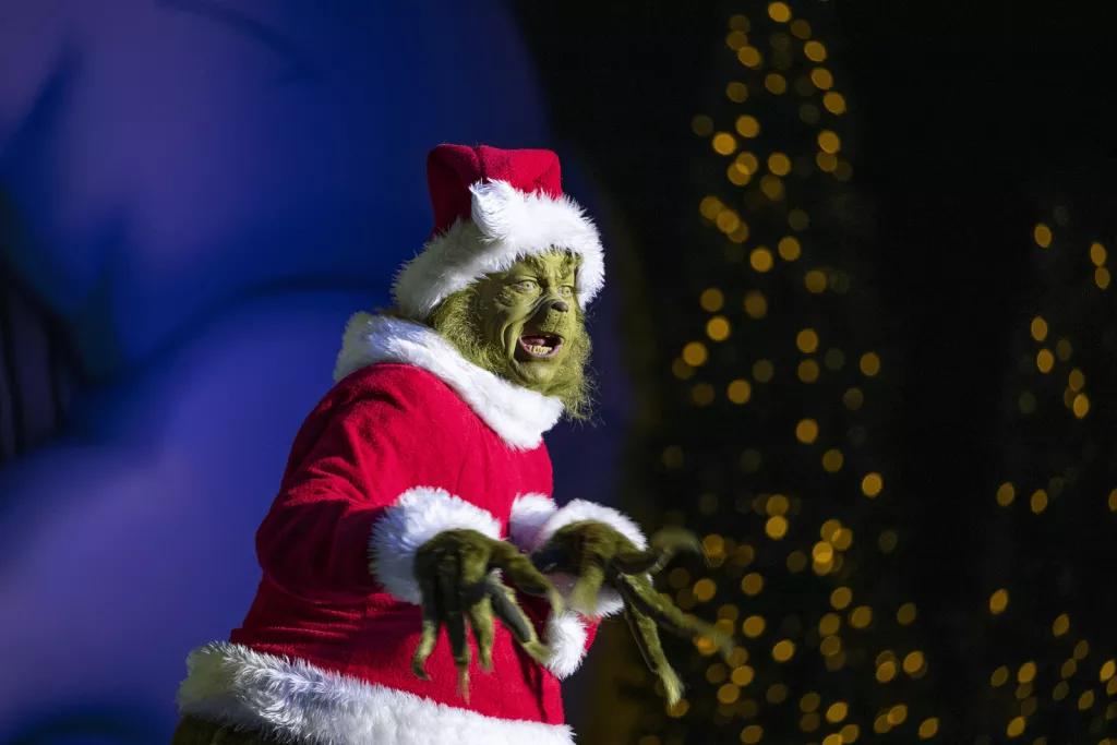 The Grinch dressed as Father Christmas standing on a stage