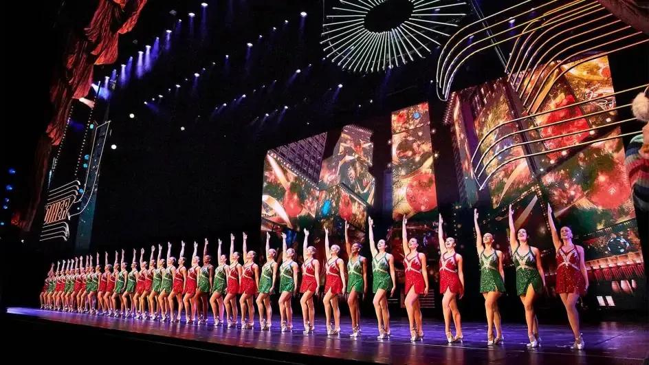 A line of dancers in sparkly leotards on stage facing the audience