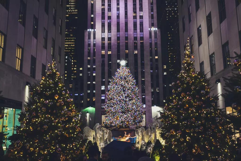 A giant Christmas tree lit up in Rockefeller Center, in front of a skyscraper