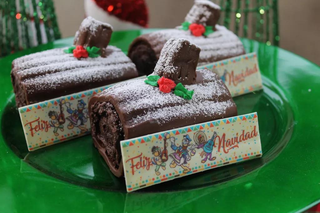 Mini chocolate yule logs dusted with icing sugar, with a piece of chocolate that reads Feliz Navidad