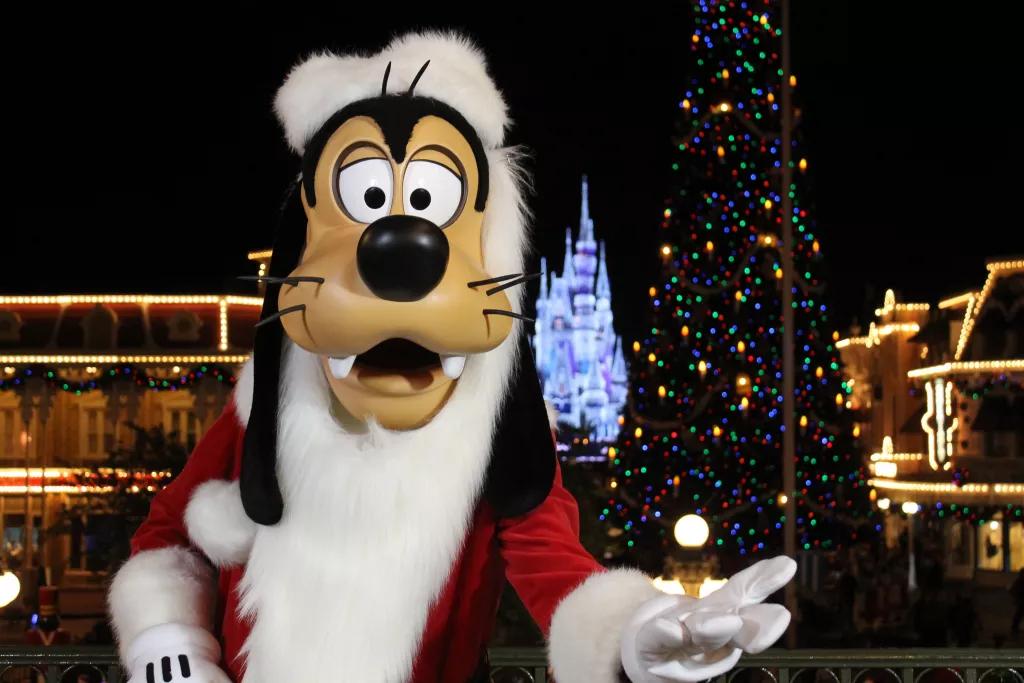 Goofy dressed as Santa Claus with a lit up Cinderella Castle in the background
