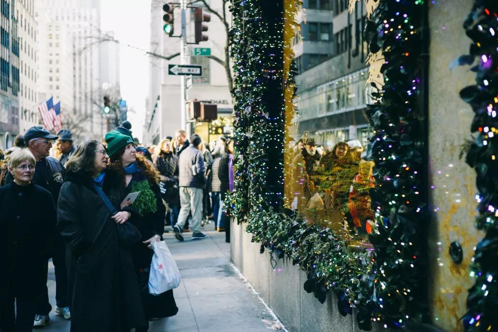People walking along Fifth Avenue looking in shop windows decorated for Christmas