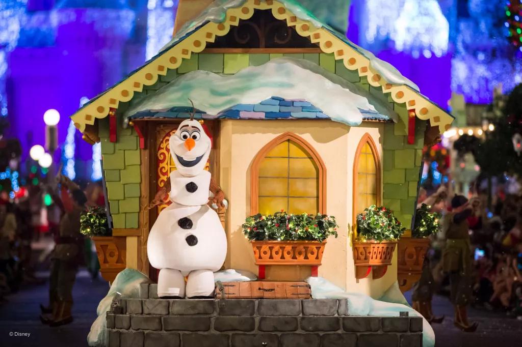Olaf the snowman on a parade float designed to look like a house