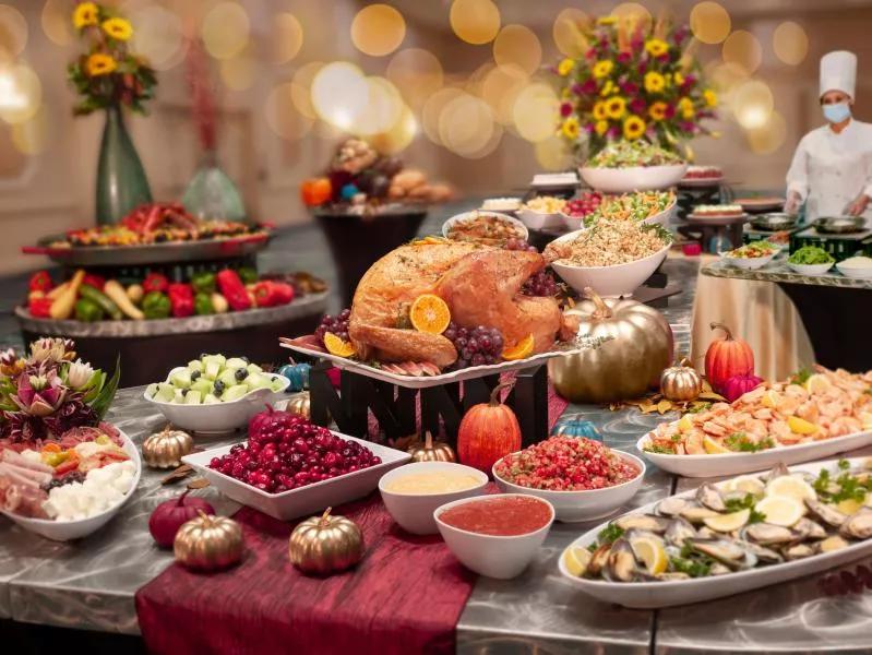 A table full of Thanksgiving foods, including turkey, cranberry sauce, stuffing and shrimp