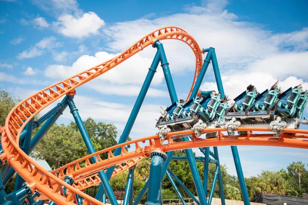 A ride vehicle on a bright orange and blue twisting roller coaster track