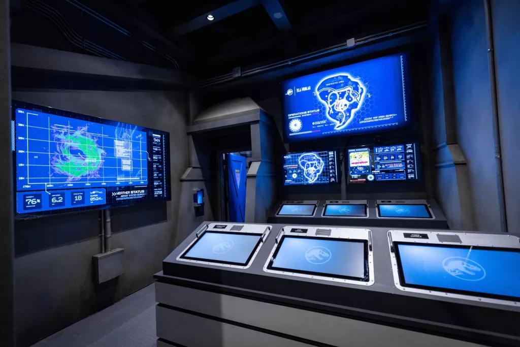 A dark room filled with screens on countertops and on the walls showing statistics and other information
