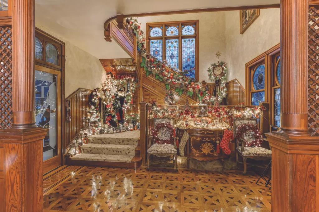 A large old fashioned staircase decorated for Christmas with stockings and garlands