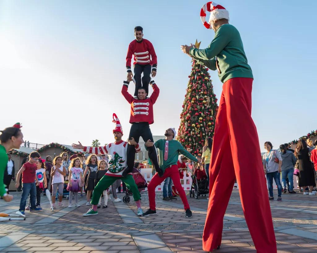 Acrobatic performers dressed like elves, performing stunts and walking on stilts