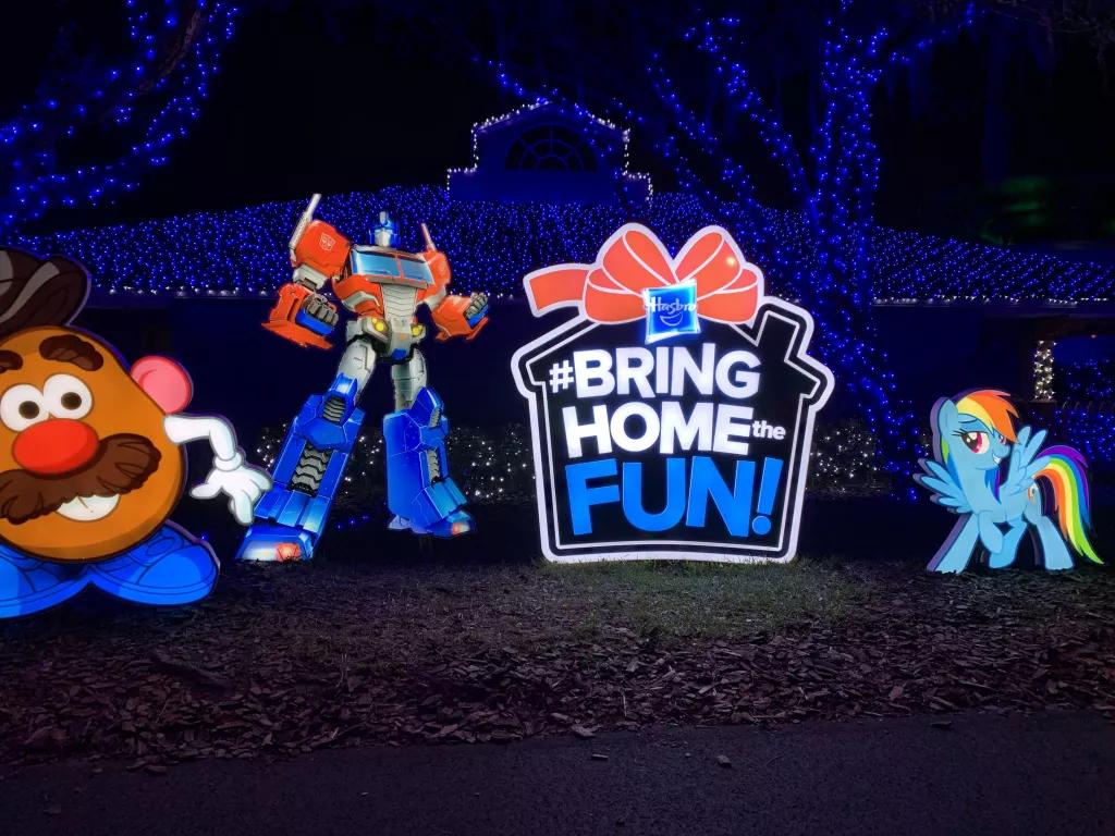 Large lit up decorations of children's toys and a large present saying "Bring Home The Fun"