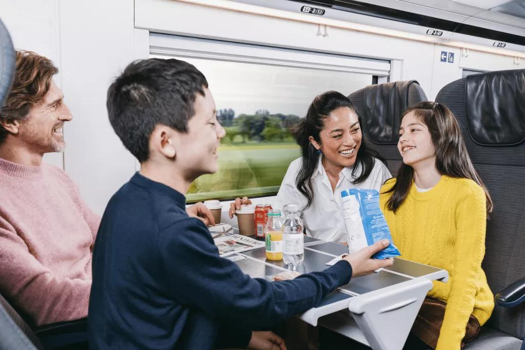 A family of two adults and two children eating snacks on a Eurostar train