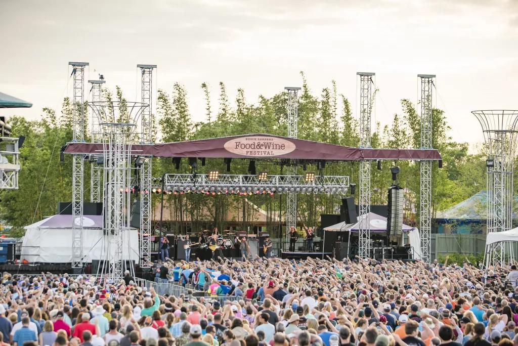 A large crowd of people watching a concert on an outdoor stage