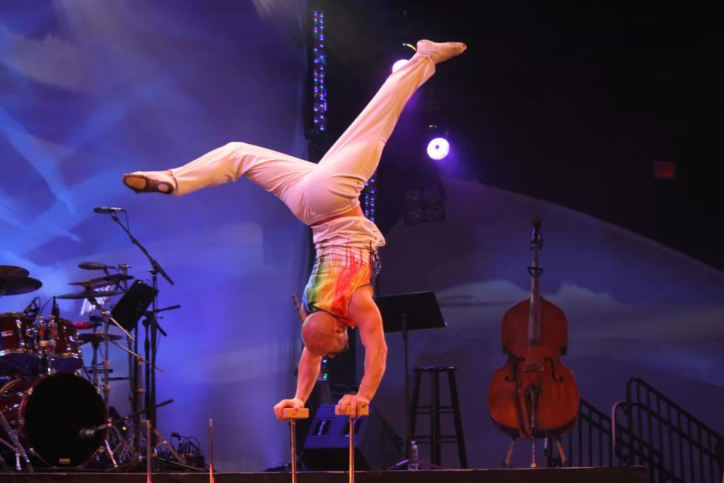 An acrobat on a stage doing a hand stand on two poles