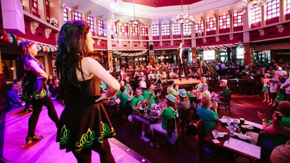 Two Irish dancers on a stage looking out over a full restaurant