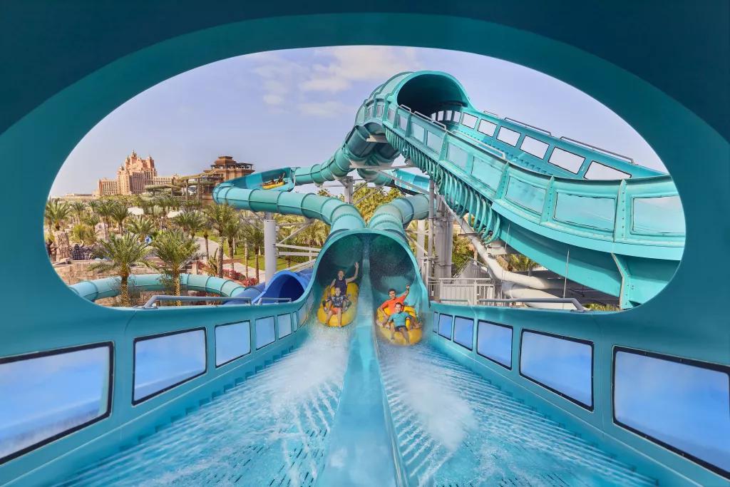 Two duelling waterslides next to each other with people in rafts coming out the bottom of the tube