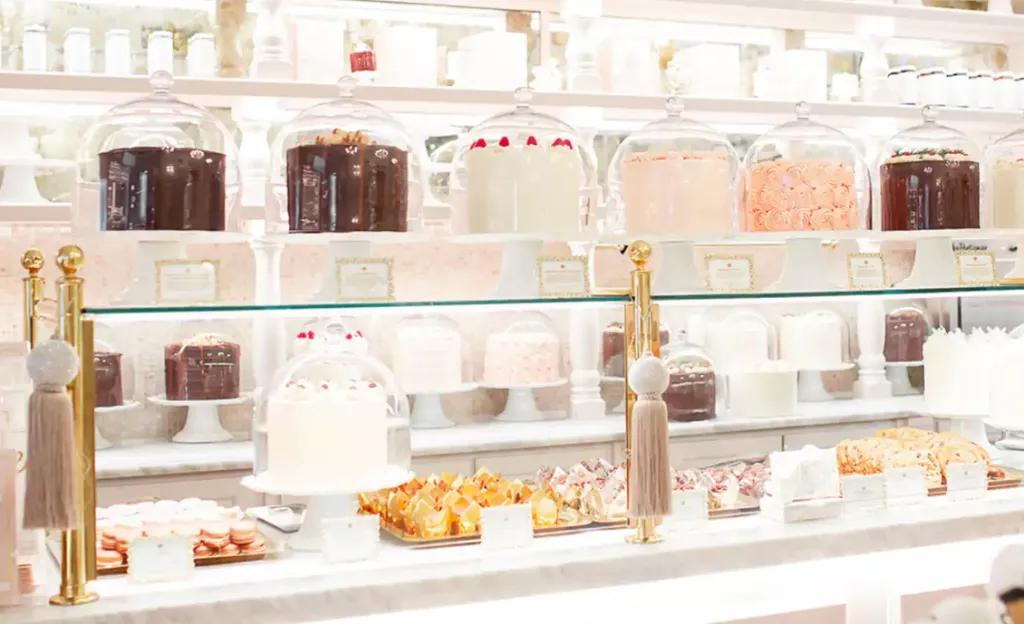 A glass display cabinet full of layer cakes and individual pastries