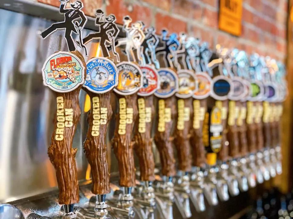 A line of beer taps designed to look like tree branches, labelled with "Crooked Can" in gold lettering