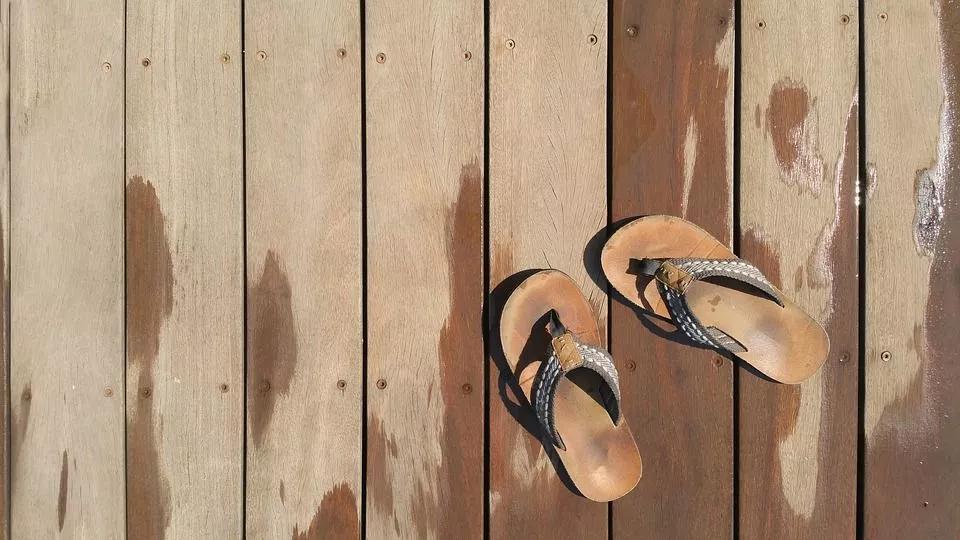 A pair of flip flops on a wet wooden deck