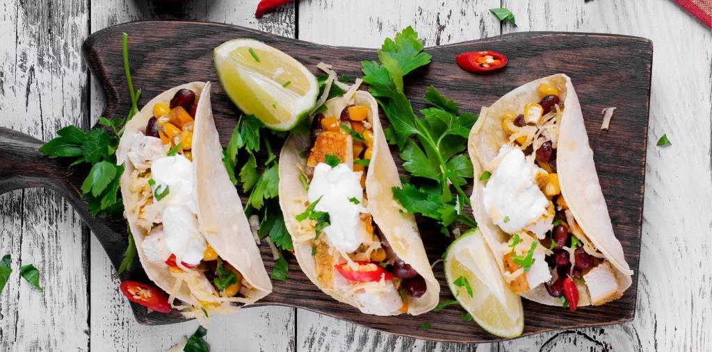 Three soft tacos filled with chicken, beans, corn and cheese