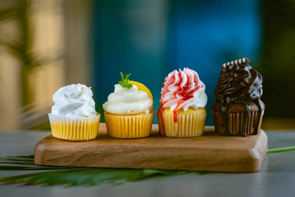 4 different flavoured cupcakes on a wooden board