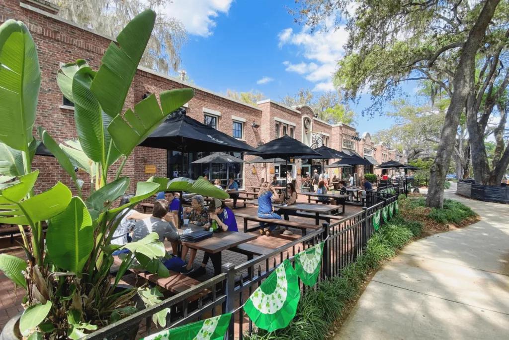 Outdoor seating outside of a brick building next to a path lined with trees