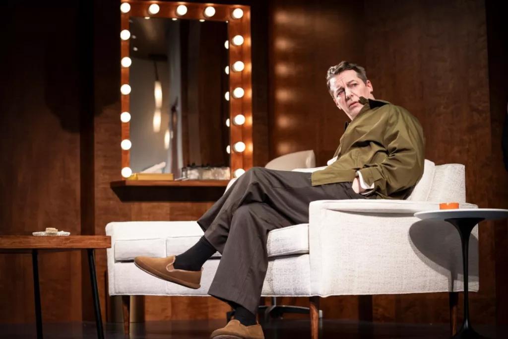 An man sat on a white sofa next to a mirror, looking off into the distance