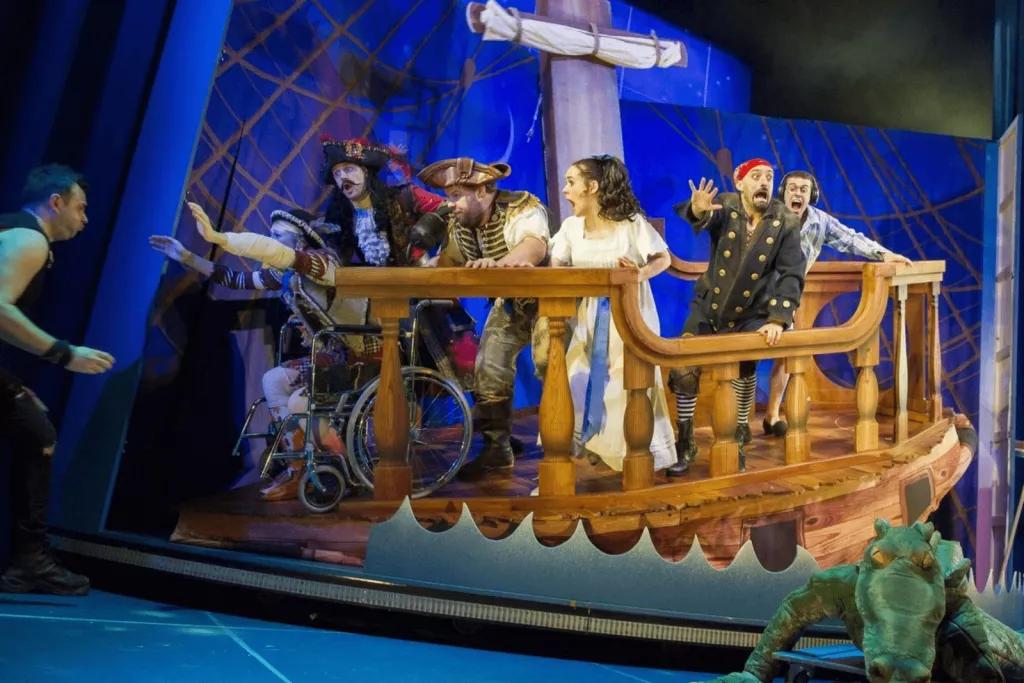 Actors playing Wendy, Captain Hook and other pirates from Peter Pan on a stage set to look like a pirate ship